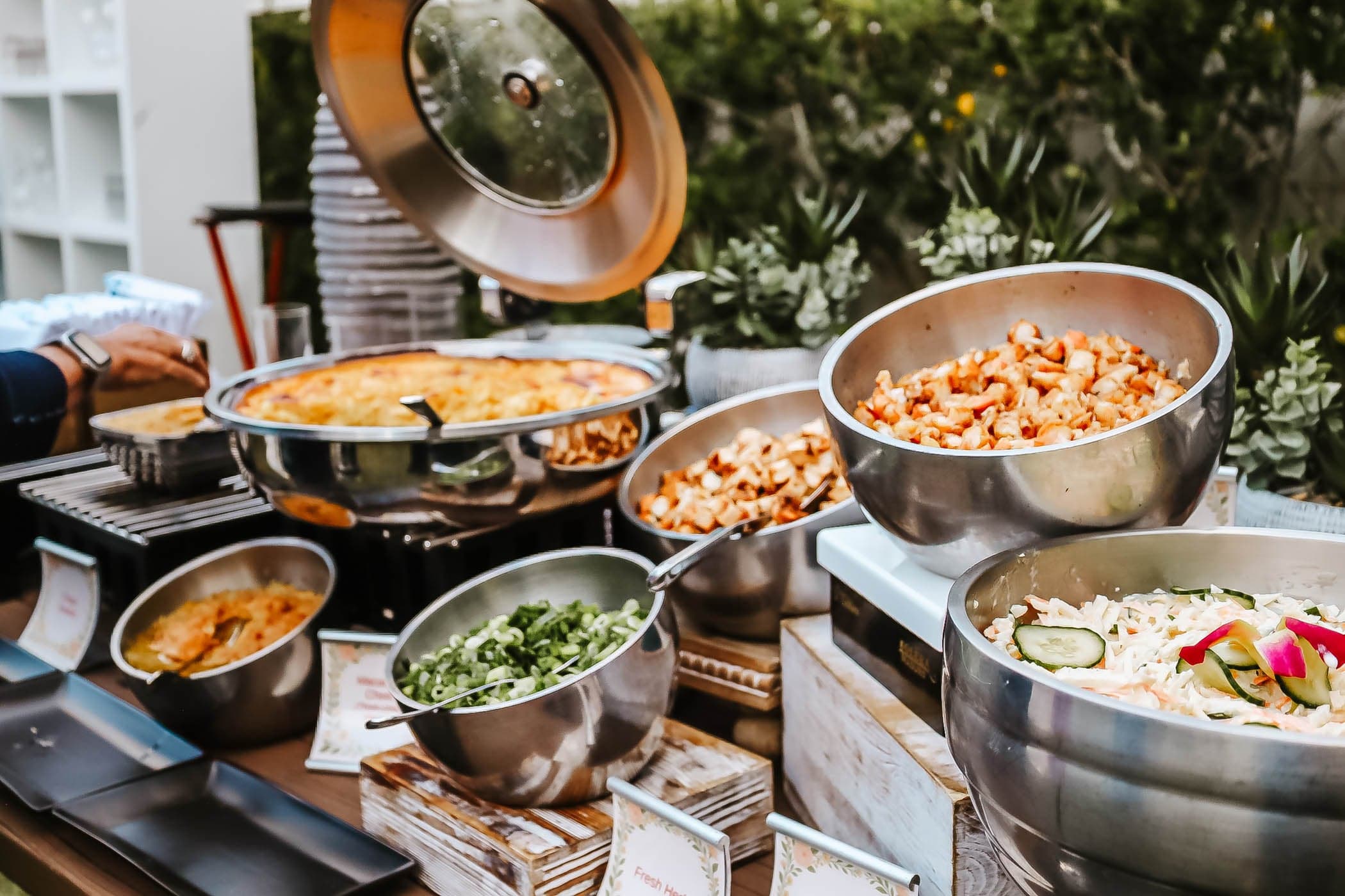 A bunch of catering dishes in serving bowls at a catering event station