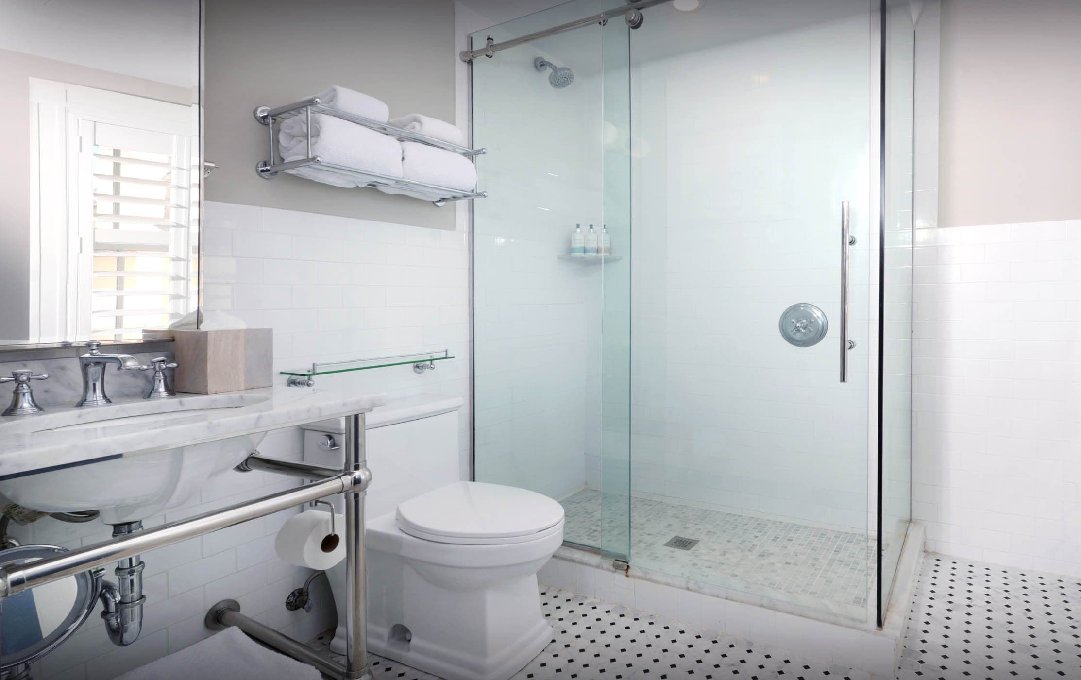 A standard bathroom with a single sink, stand up shower and toilet.
