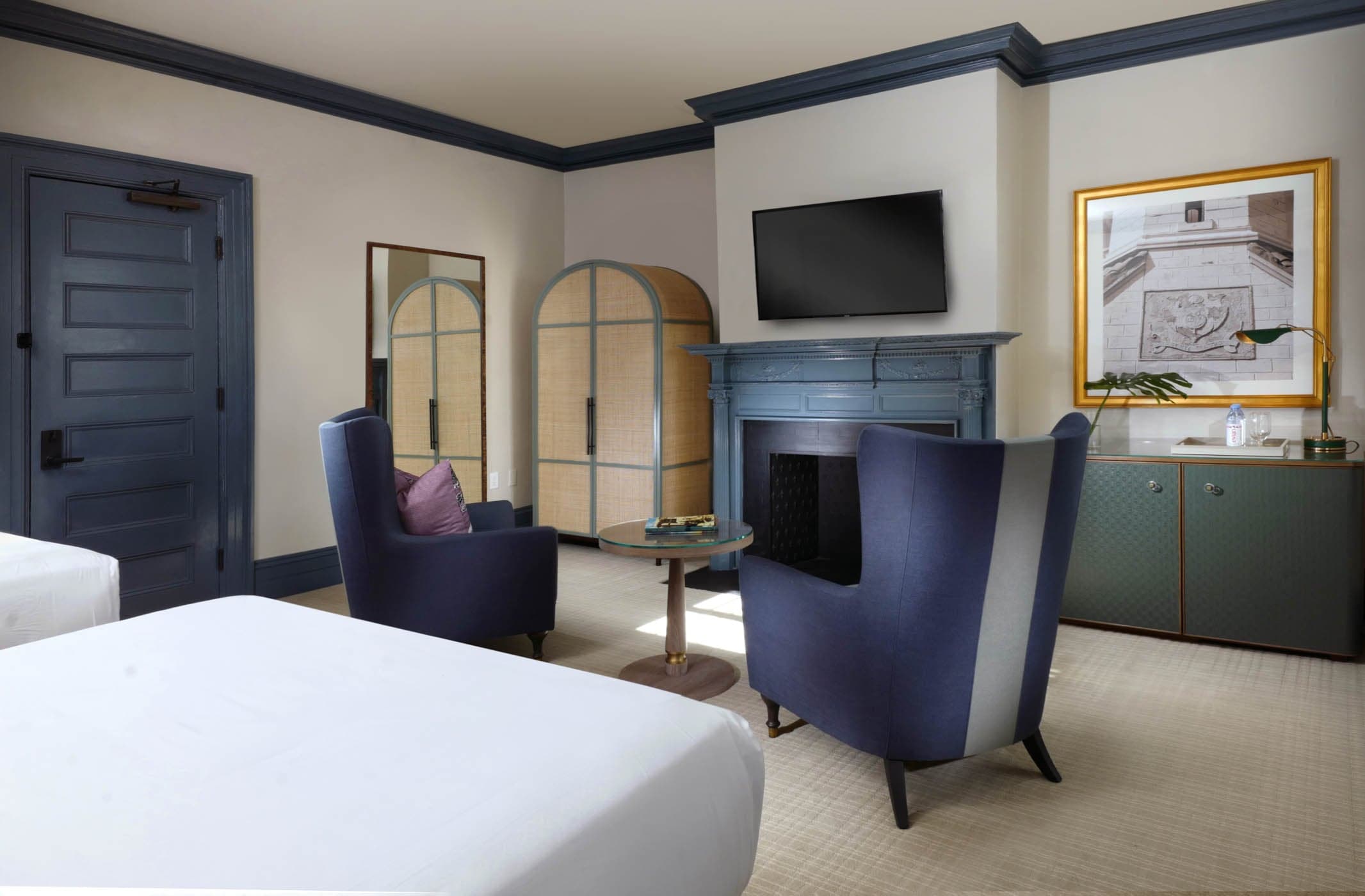 2 chairs and a fireplace at the end of a the bed in a Clubhouse Traditional Two Queen