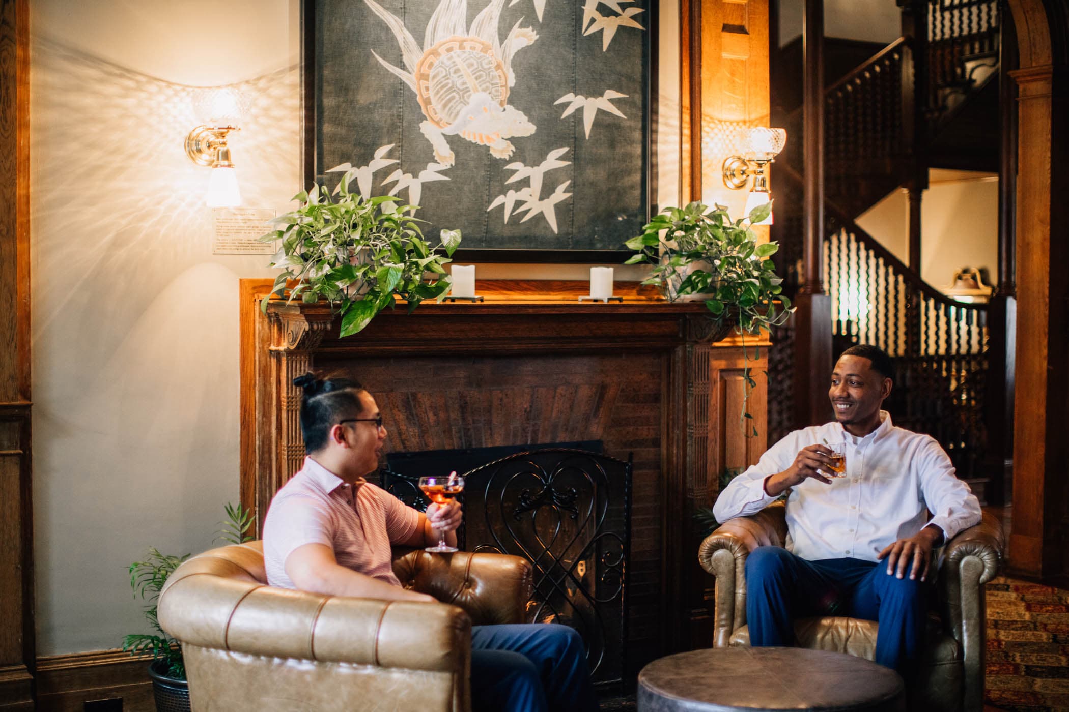 Two people enjoying cocktails beside a fireplace