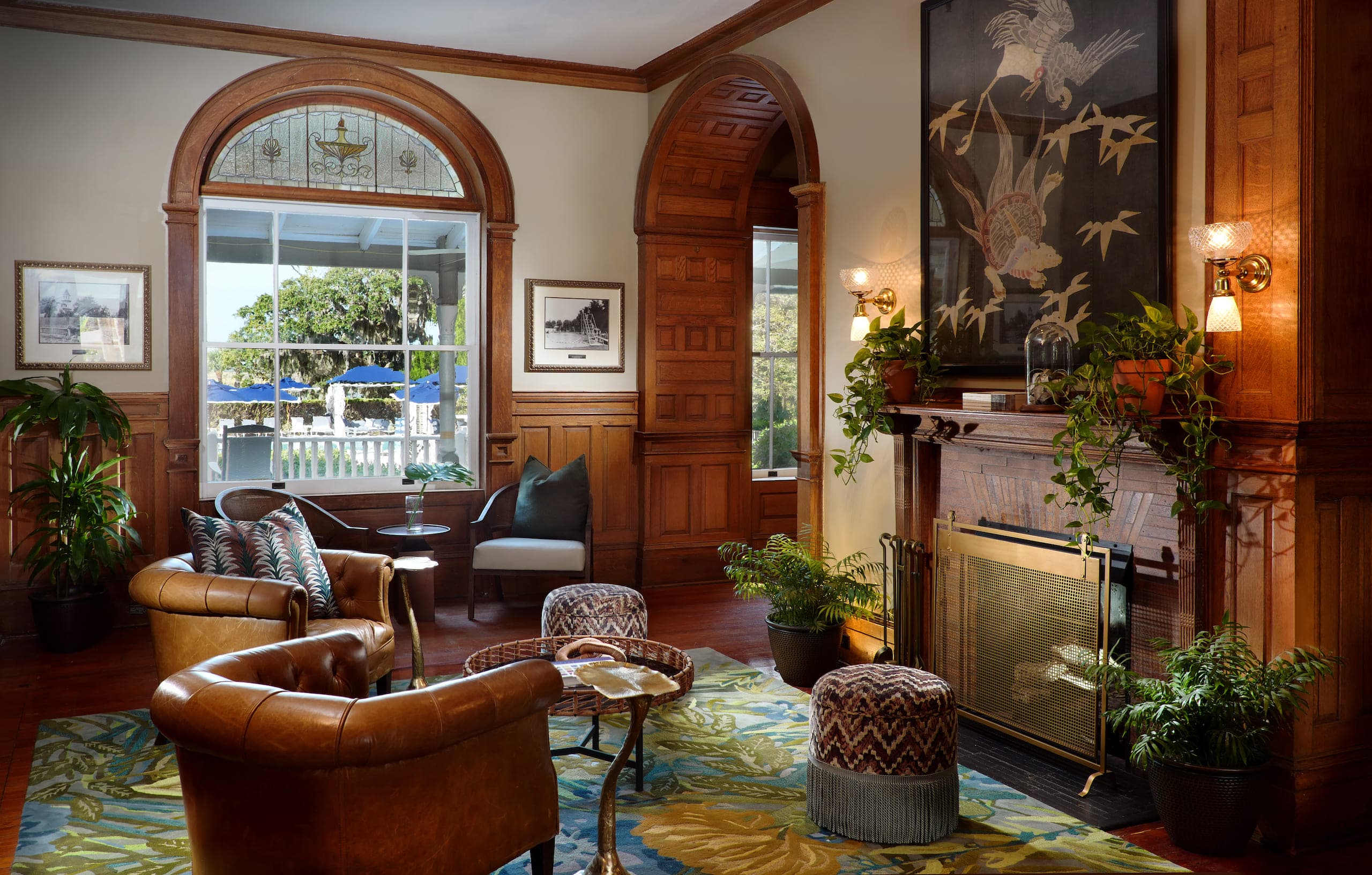 A room with wood panel walls, 2 leather chairs facing the fireplace and beautiful arched doorways