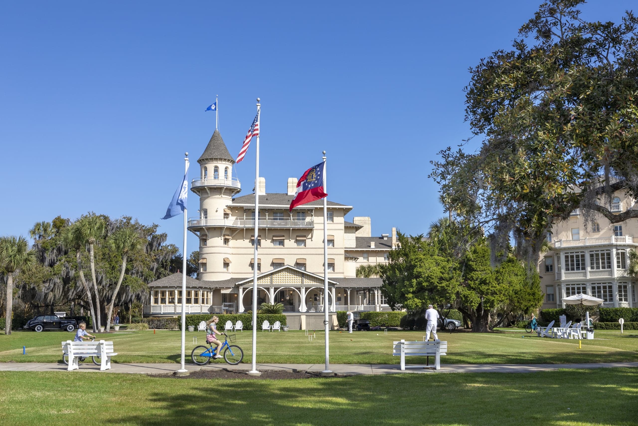 People playing croquet and a person riding a JICR rental bike out front of the resort