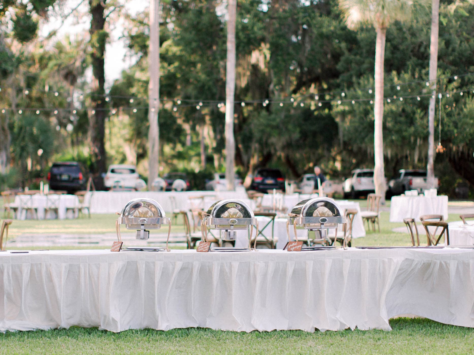 A table set up with chaffing dishes at an outdoor wedding