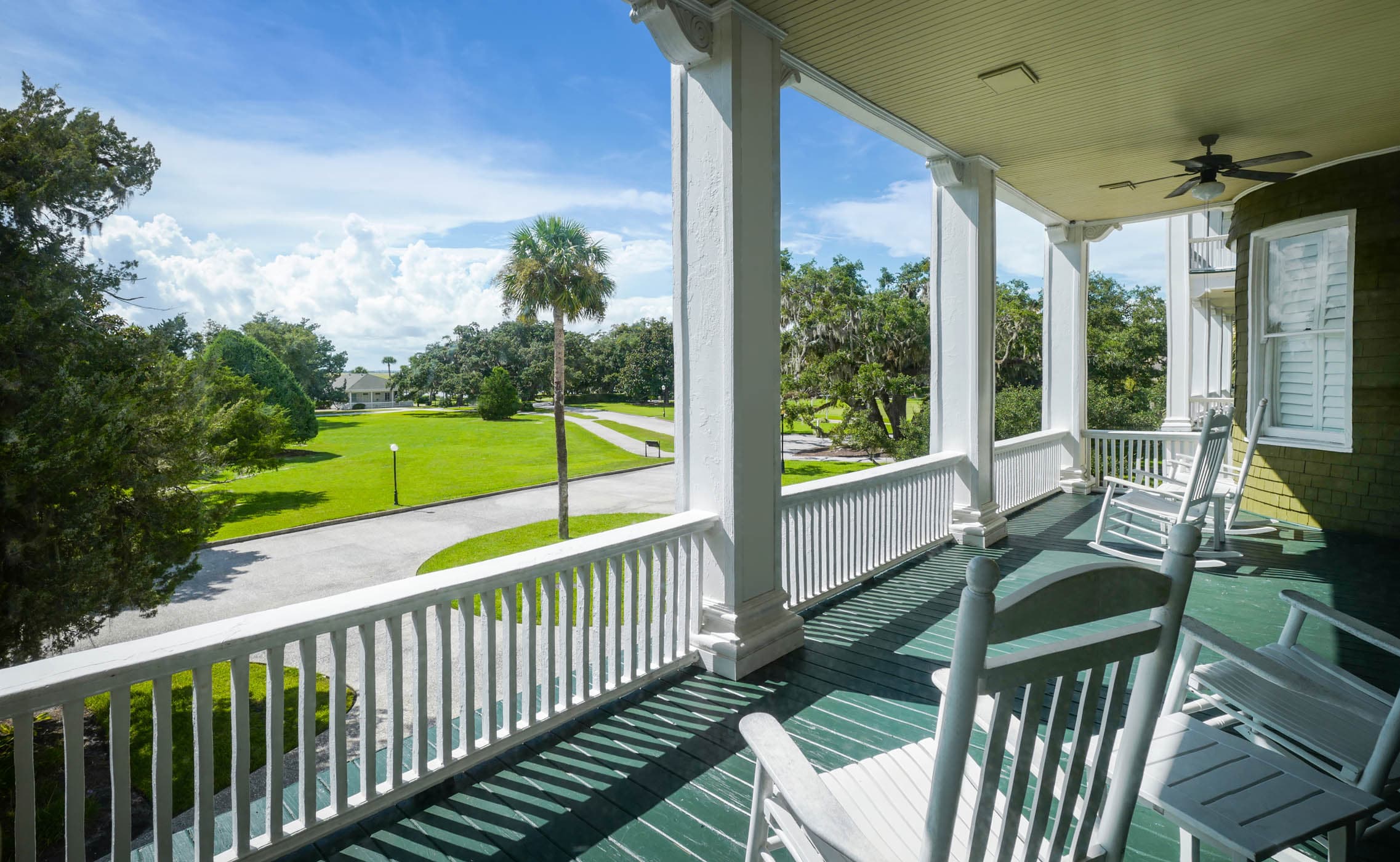 A balcony with 3 rocking chairs and a small table