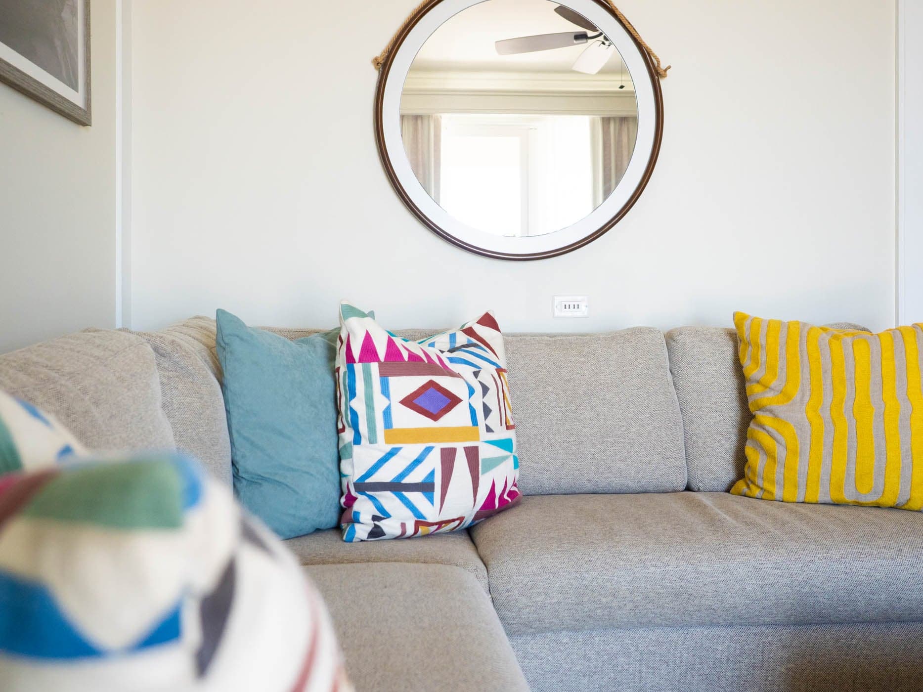 A sectional couch with a round mirror above it at Jekyll