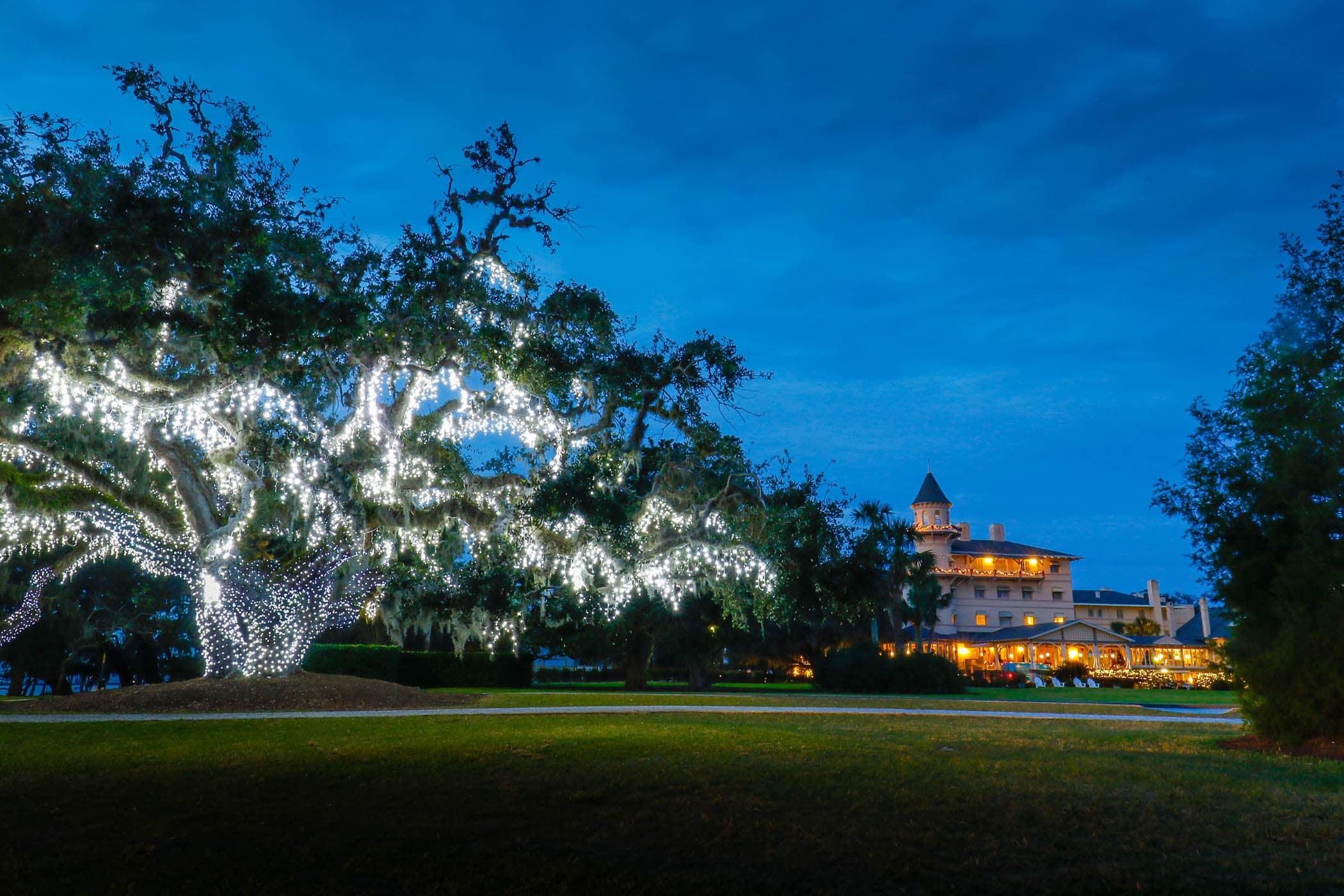 The exterior of Jekyll Island at night with a tree decorated with lights