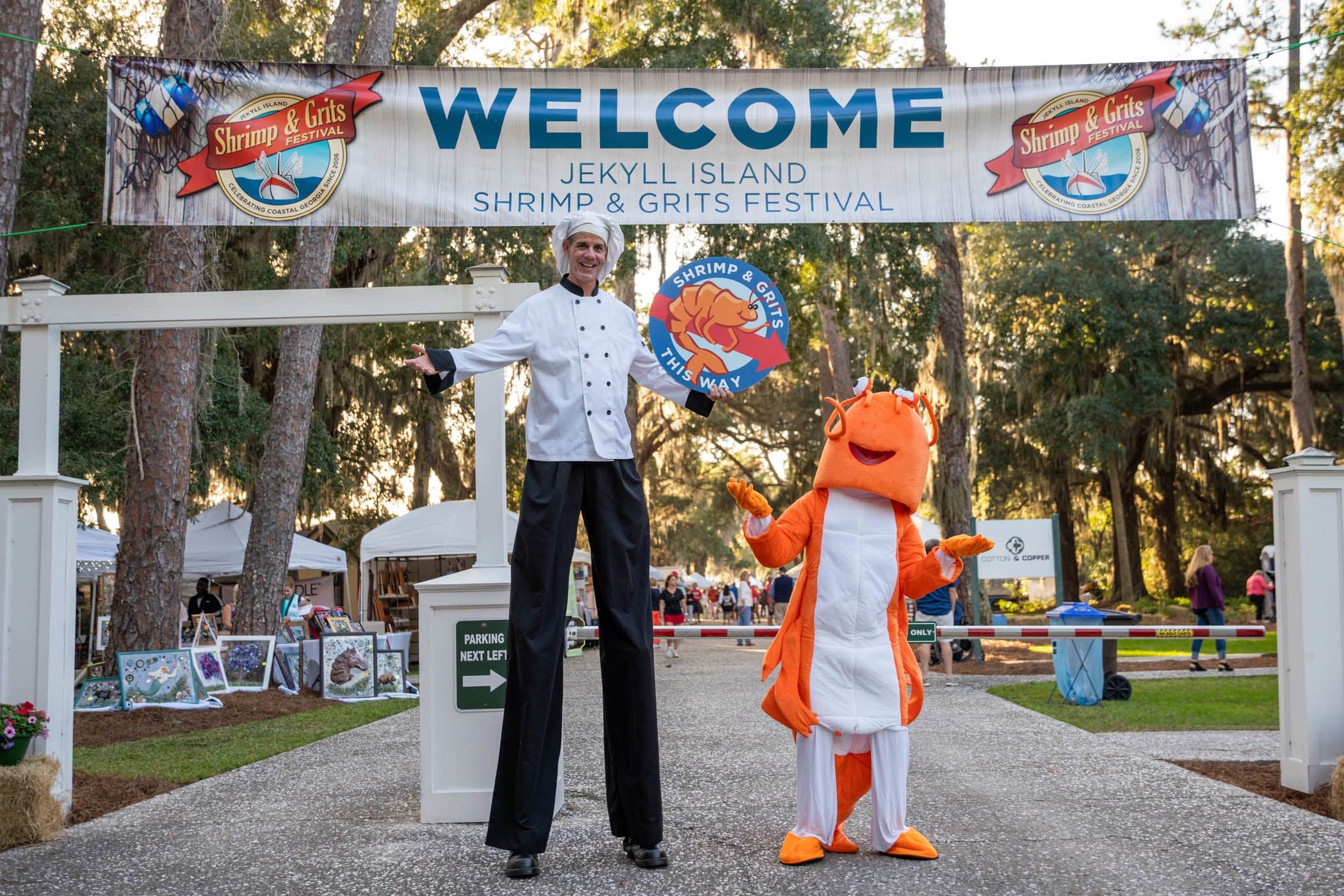 A man wearing stilts dressed as a chef and a person in a shrimp costume for the Shrimp & Grits festival