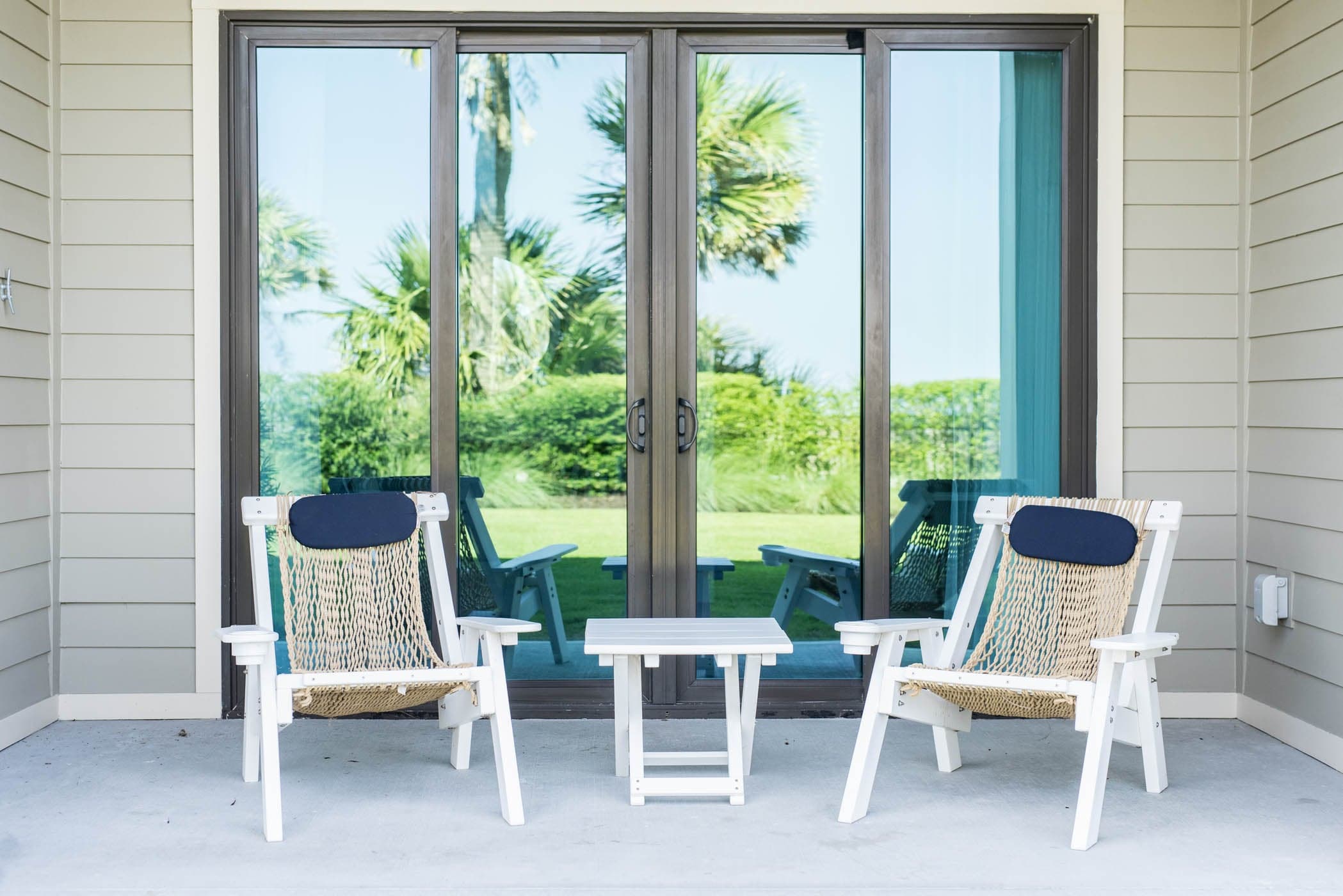 A patio with 2 chairs and a small table between