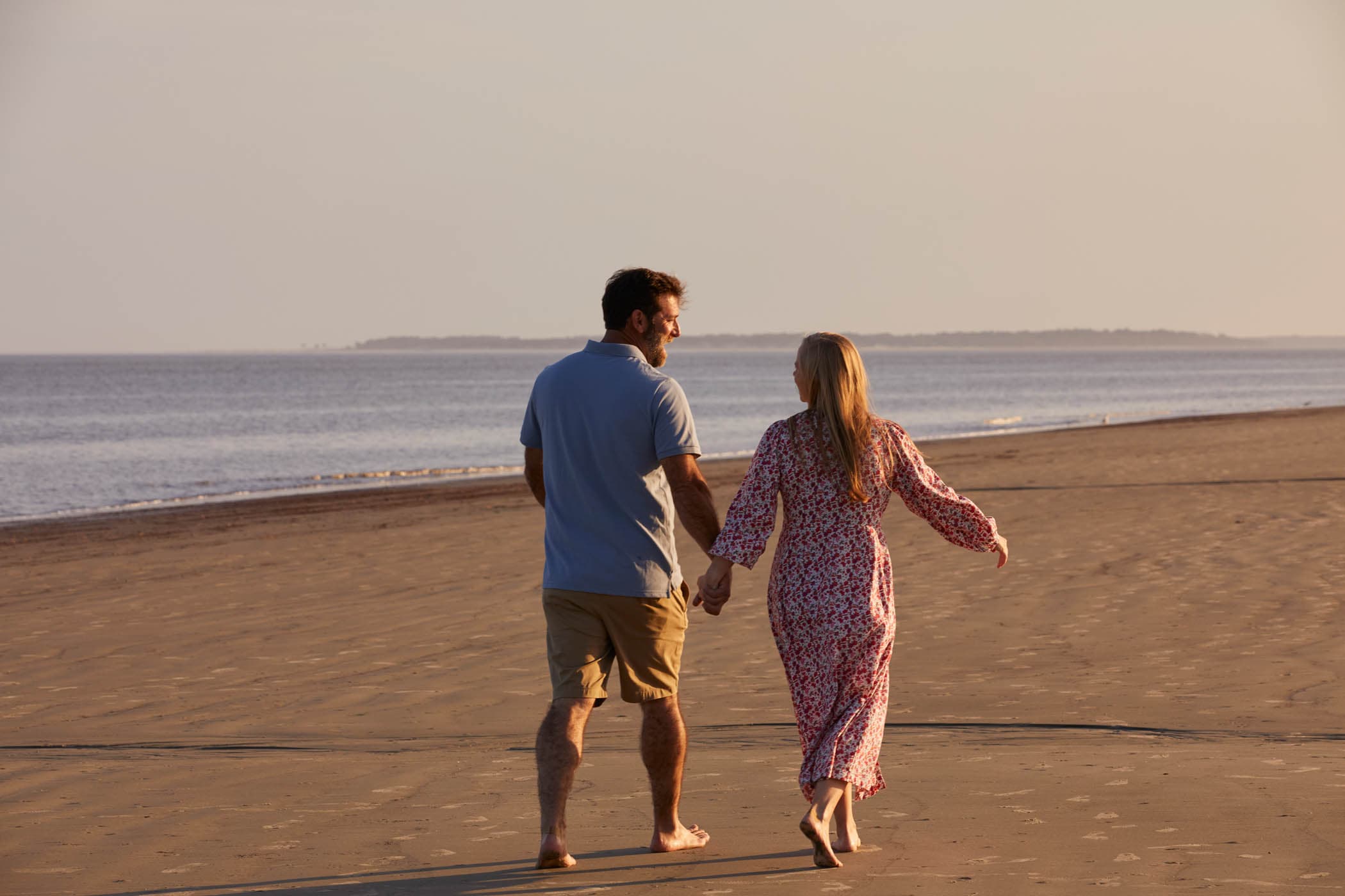 A couple waling on the beach holding hands