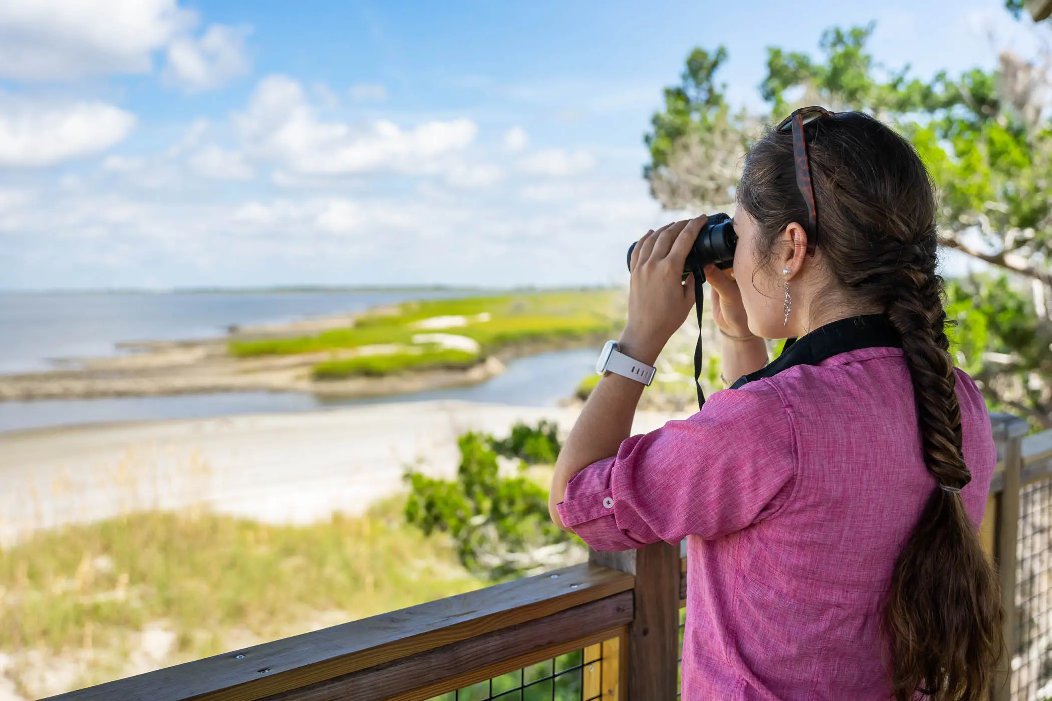 A woman looking off a lookout with binoculars