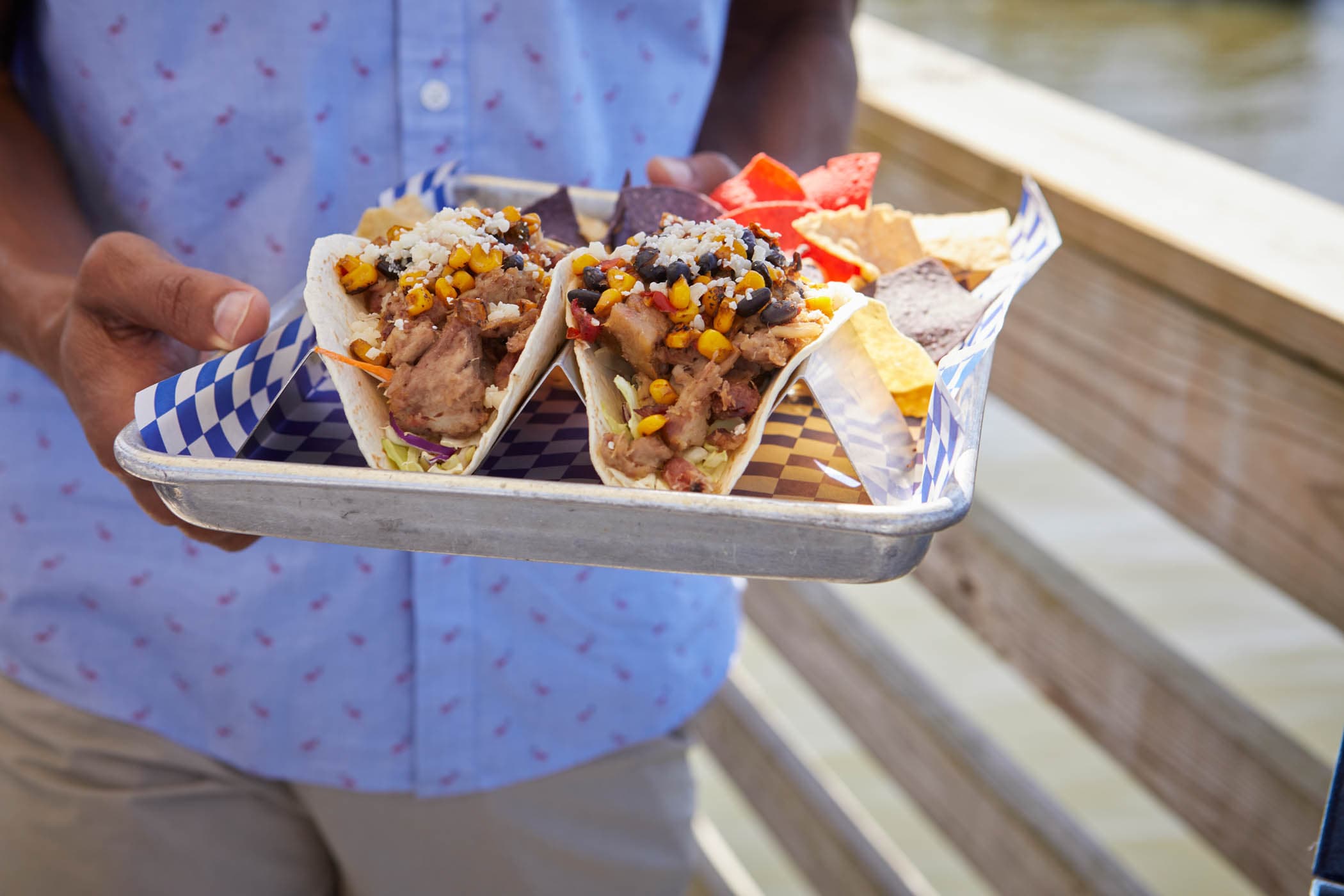 a man holding 2 tacos with tortilla chips