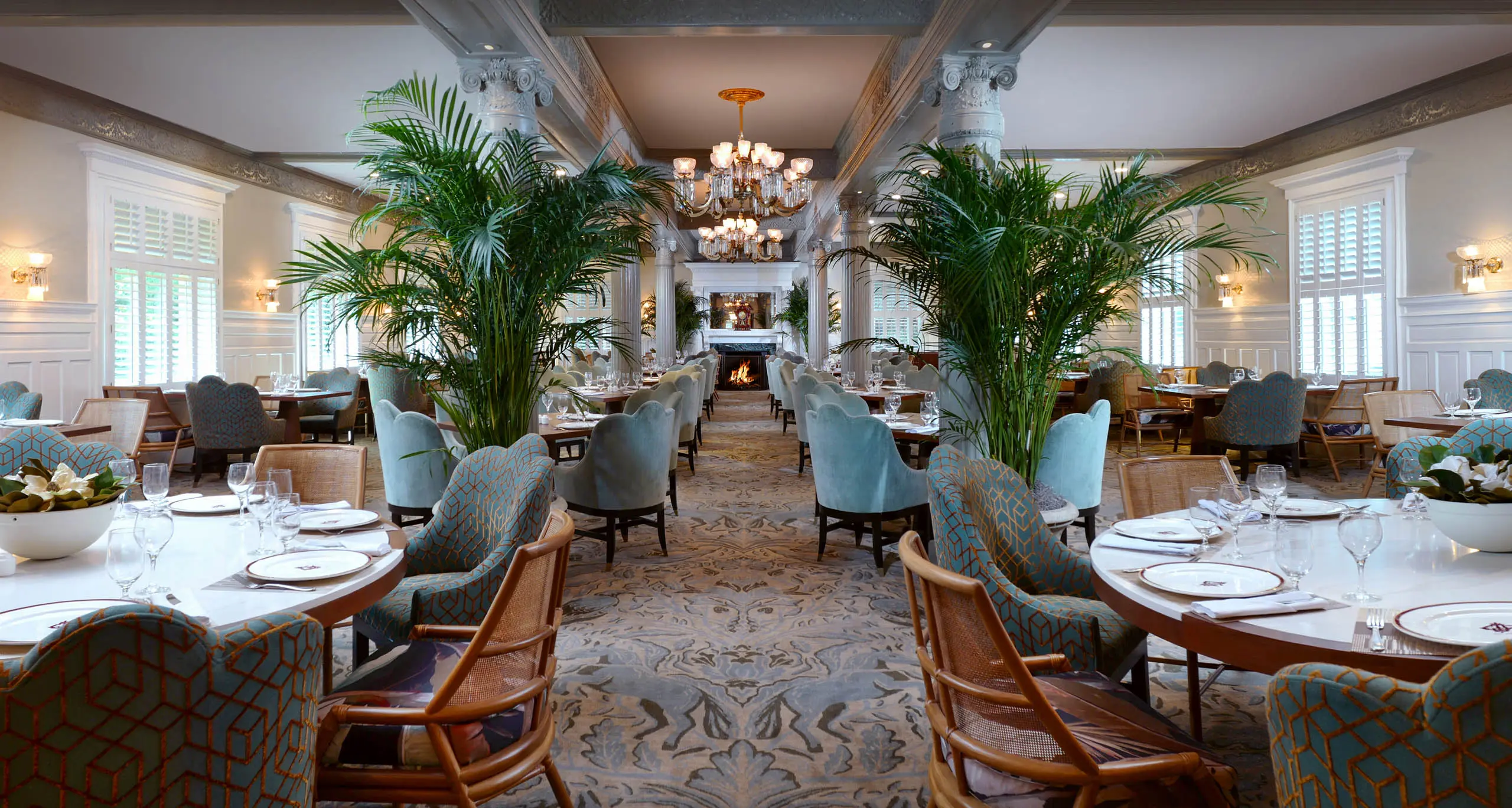 The interior of the Grand Dining Room with lots of table seating and beautiful large fern trees