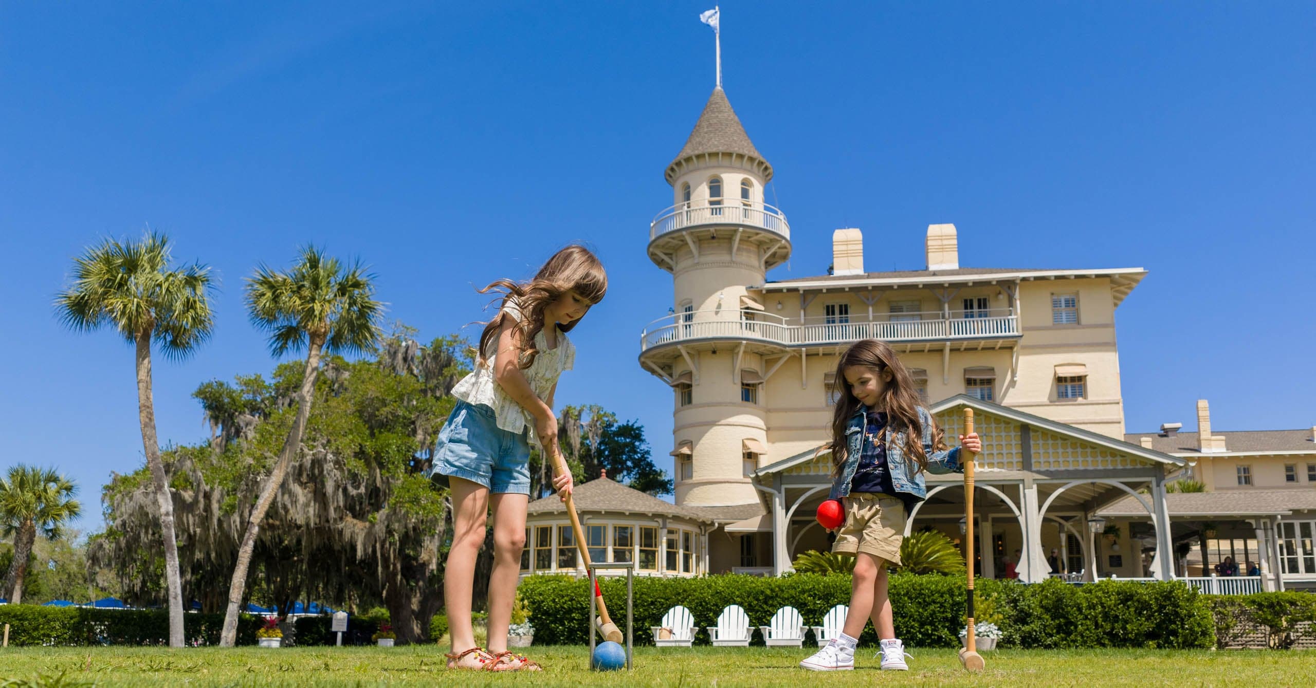 Two children playing croquet out front of JICR