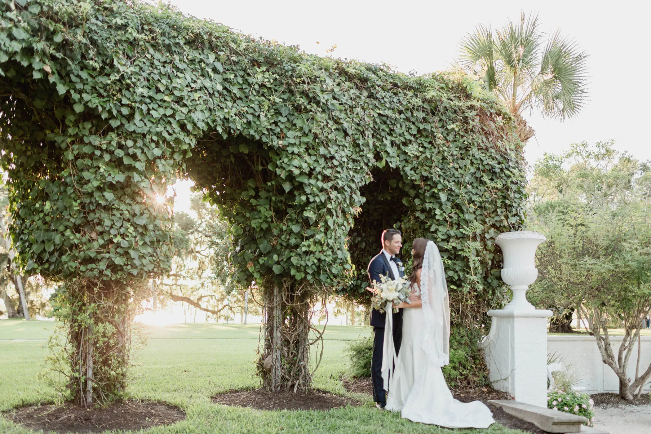 A married couple embracing by manicured trees at Jekyll