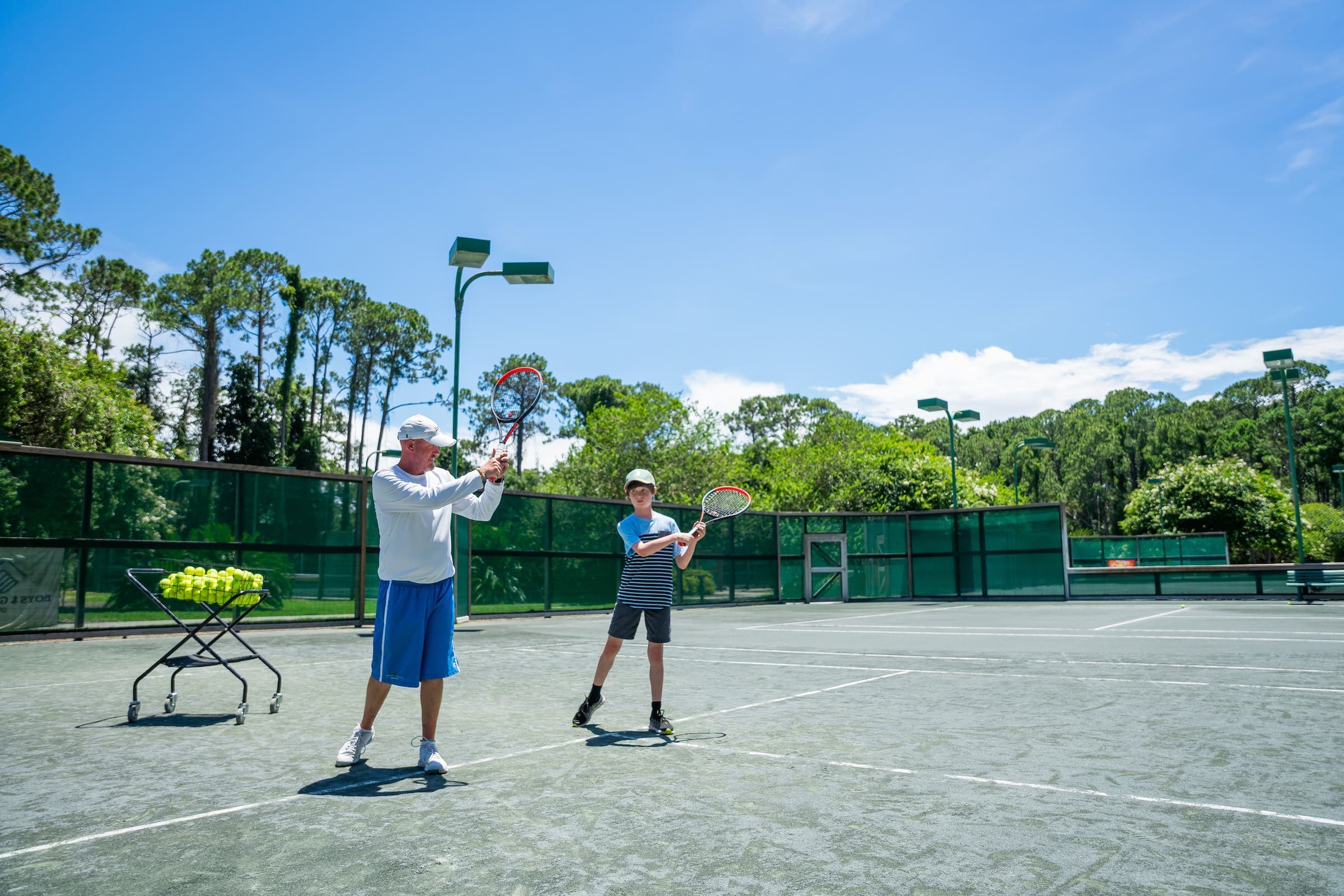 A young tennis kid learning how to play tennis by an instructor