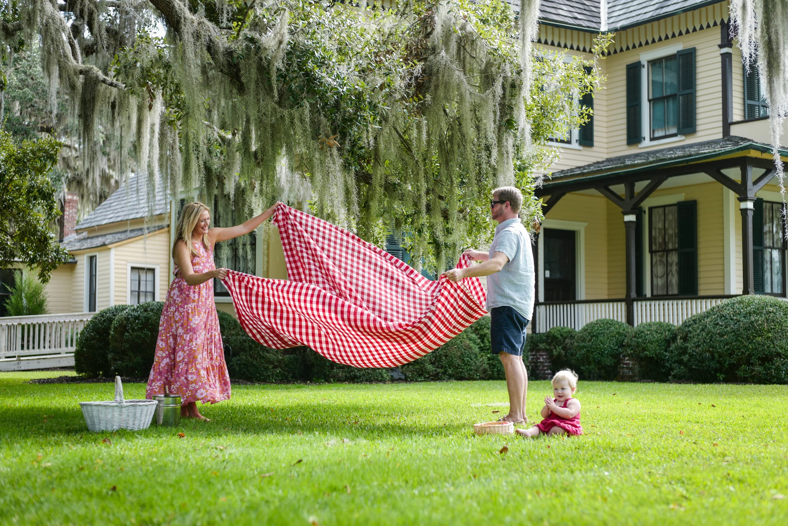 A man and woman setting up a blanket on the ground for a picnic