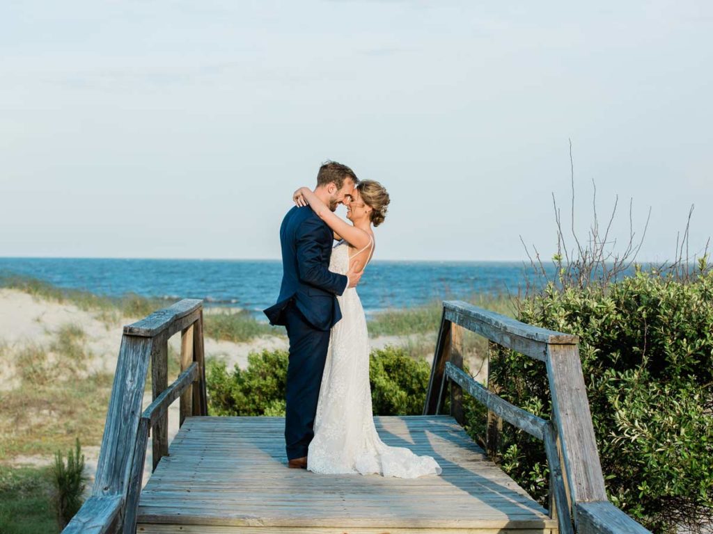 Bride And Groom On A Walking Bridge By The Beach.