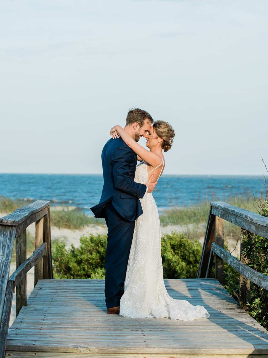 Bride And Groom On A Walking Bridge By The Beach.