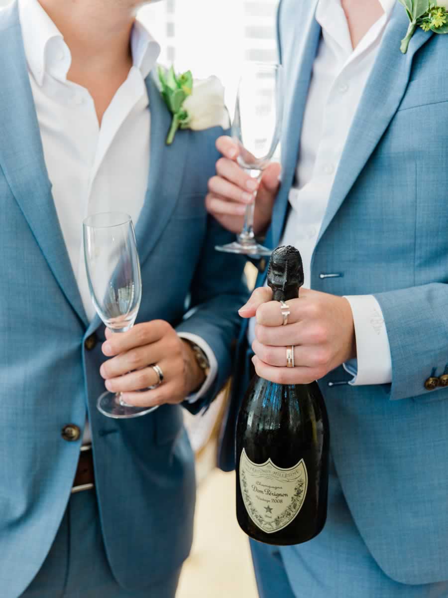 Groom and groomsman celebrating with champagne